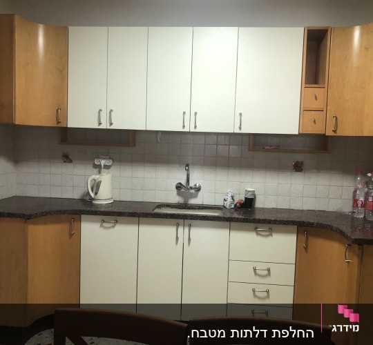 מטבח עם ארונות עץ, קומקום חשמלי וכיור